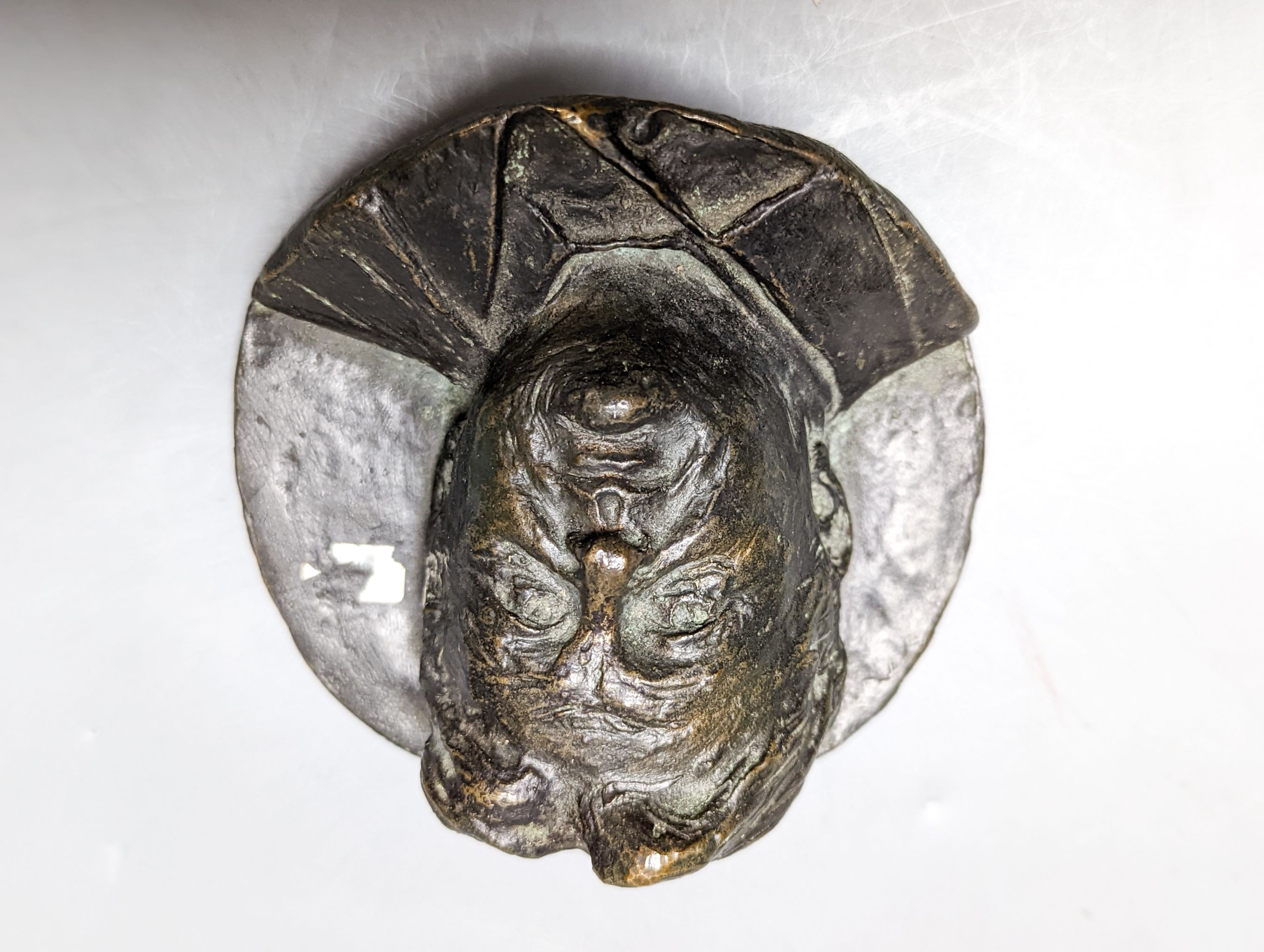 A bronze ram's head and a bronze relief